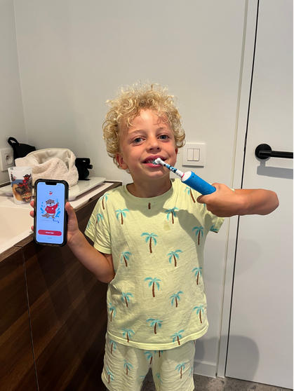 Child brushing while holding a phone with Otty